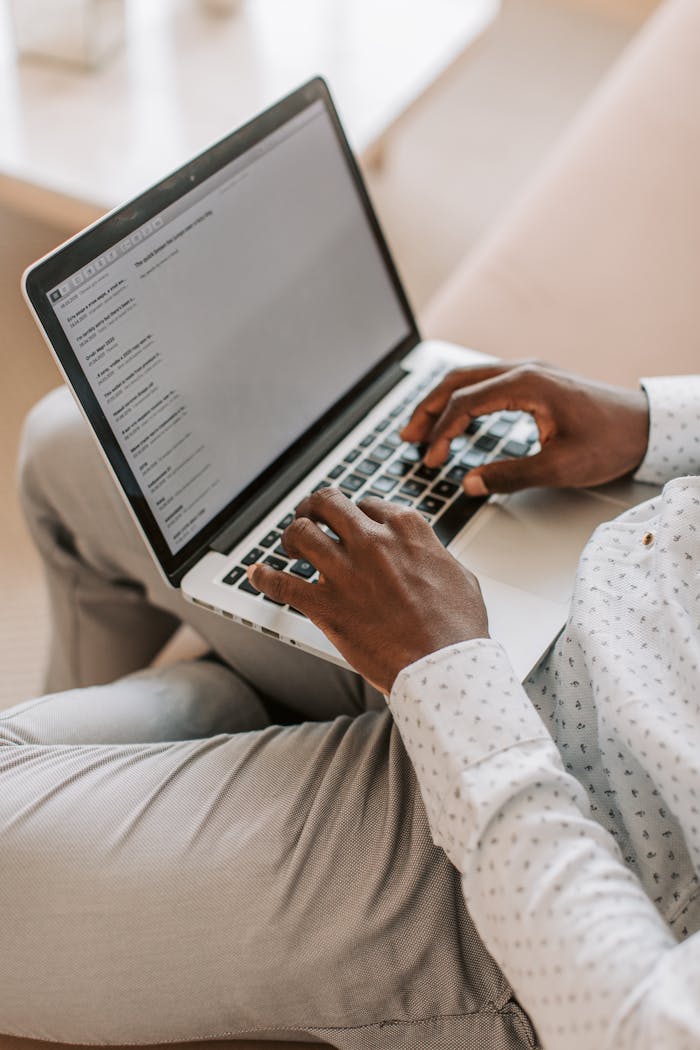 An adult typing on a laptop in a cozy home environment, focused on work.